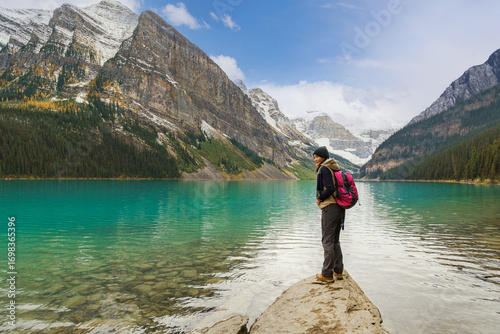 Lake Louise, Canada: An adventurous spirit enjoys the breathtaking beauty of Banff National Park, proudly standing on a rock overlooking the famous lake