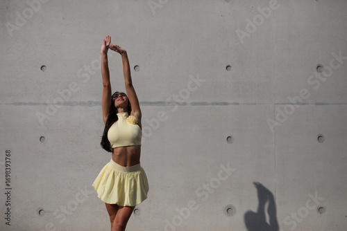 young woman in yello short dress walking on the street in the evening
