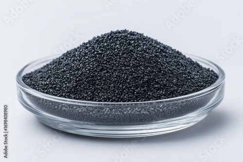 Activated carbon granules in glass bowl, isolated on white background for water filter and purification concept