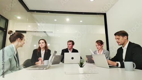 Business team collaborates in modern office during a strategic meeting with laptops and documents
