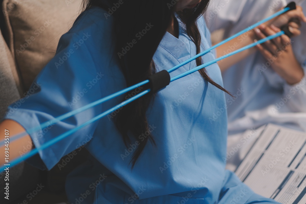 Obraz premium Doctor physiotherapist assisting a male patient while giving exercising treatment on stretching his arm with exercise band in the clinic, Rehabilitation physiotherapy concept