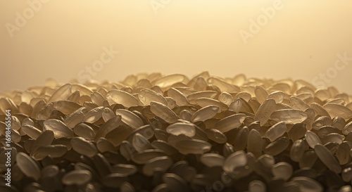Pile of translucent rice grains illuminated with a warm golden light creating shadows and highlights on the grain surfaces