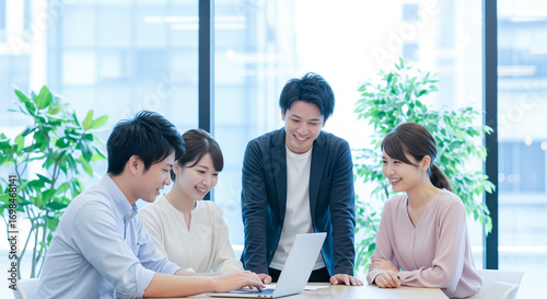 4人の日本人ビジネスパーソンがノートパソコンを使って行うオフィスでのチームディスカッション