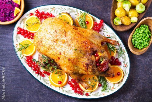 Roasted whole duck with fuits and berries served on oval side dish plate. High angle view