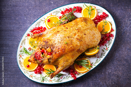 Roasted whole duck with fuits and berries served on oval side dish plate. High angle view