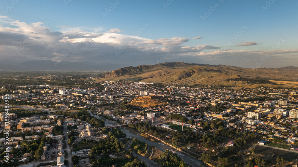 Fototapeta premium Drone view of Gori city with river, houses, and fortress surrounded by mountains