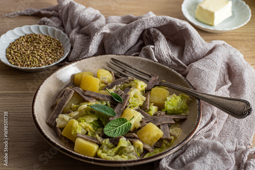 Pizzoccheri Valtellinese. Northern Italian winter dish, buckwheat pasta with potatoes, cabbage, cheese and sage. Traditional mountain cuisine of Valtelina, Nord Italy, close up