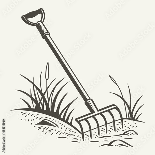 a garden rake resting on soil with grass growing nearby