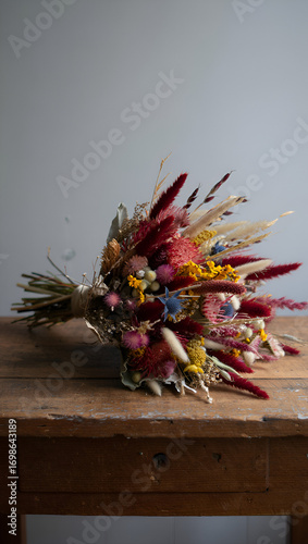 A rustic bouquet of dried flowers and grasses on a wooden table
