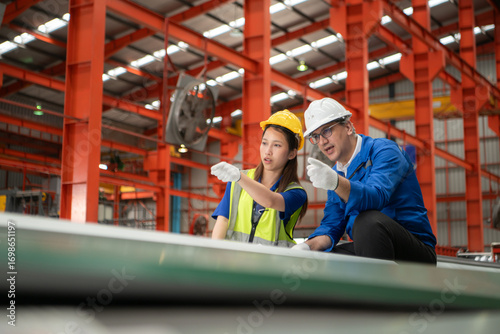 Senior engineers and young female workers are talking and inspecting steel plates