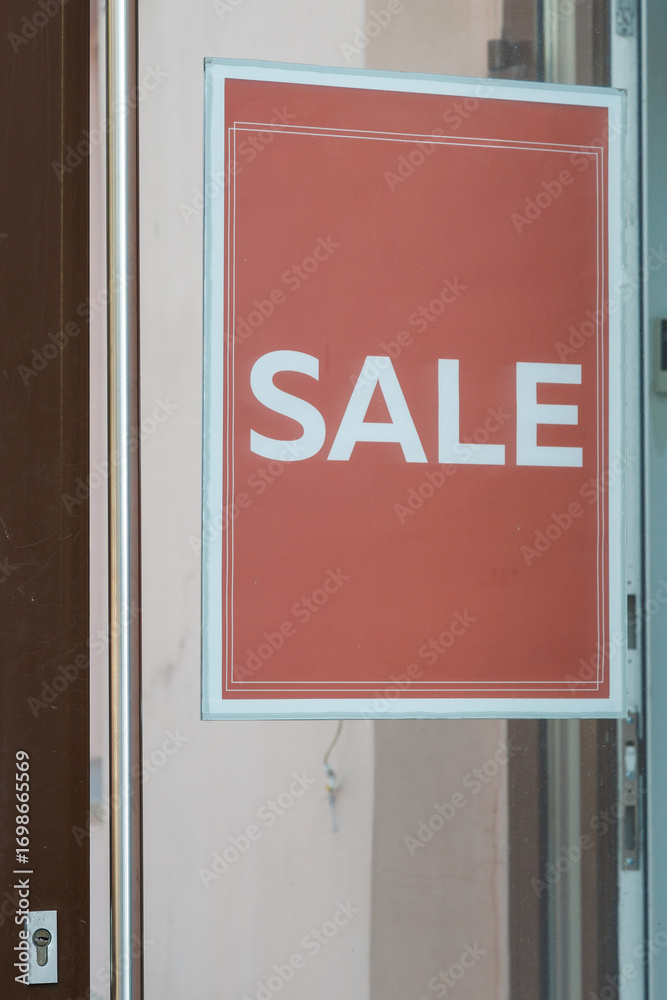 The inscription SALE in white paint on a red background on the glass door of the store. The inscription SALE in white paint on a red background on the glass door of the store.
