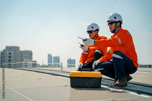 Obraz na plátně Workers assess solar panel installation on rooftop in urban setting during sunny
