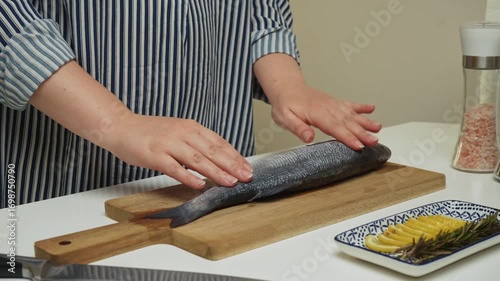 Female hands preparing the sea bass fish for cooking at home kitchen. Concepts of healthy eating and seafood
