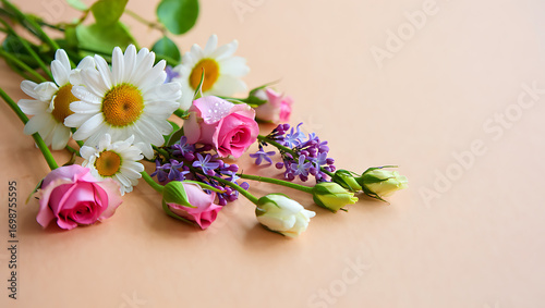 A delicate arrangement of pink roses, white daisies, and purple lilac blossoms lies gracefully on a soft, peachtoned surface, creating a serene and inviting floral composition with a touch of elegance