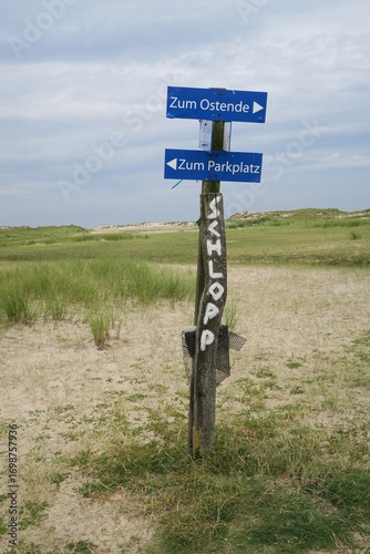 Wallpaper Mural Auf der deutschen Nordseeinsel Norderney steht im Inselosten dieser hölzerne Wegweiser in der Nähe des Priels Schlopp vor Salzwiesen. Ein Pfeil weist zum Ostende, der andere zum Parkplatz. Torontodigital.ca