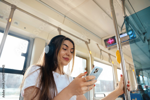 Young woman enjoying music on smartphone while commuting in public transport with headphones, urban lifestyle concept