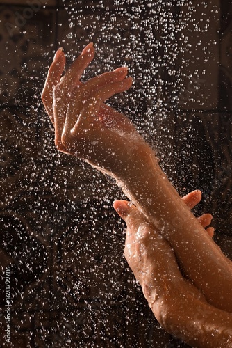 Woman's hands under shower stream with water droplets