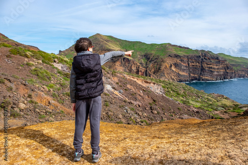 Teenage traveler points beauty Madeira, discovery archipelago landscape, volcanic island travel, adventure vacation, Atlantic Ocean adventure, ecological balance, Portugal