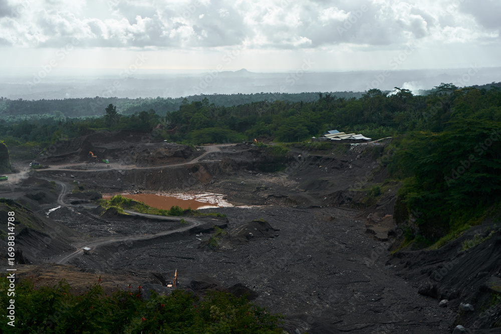 Obraz premium A stone quarry in Indonesia. Large equipment such as bulldozers and dump trucks are working on the site.