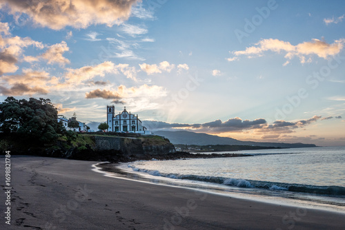 Stary portugalski kościół górujący nad czarnym piaskiem plaży i kąpieliska w Sao Roque na Sao Miguel na Azorach. Wulkaniczne plaże i zabytki Azorów