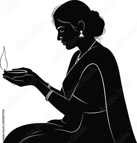 Silhouette of Indian woman wearing traditional saree holding a lit oil lamp in hands, symbolizing cultural prayer and spiritual devotion.