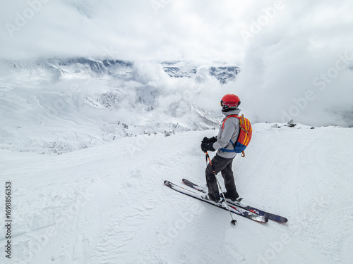Single female skier overlooking a cloud covered valley in France