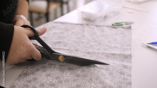 Tailor's hands cut fabric with scissors