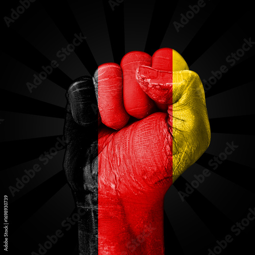 A powerful fist clenched tight, painted in the colors of the German flag, representing German Unity Day backdrop.