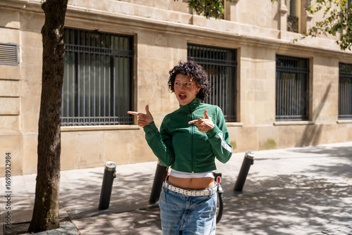Young stylish woman pointing aside while walking on city street