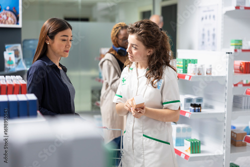 Cuadro en lienzo Healthcare worker assisting a pharmacy customer in choosing SPF cream, recommending the best sun block moisturizing products for UV light protection