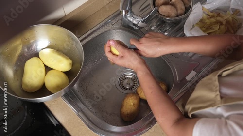 Person Peeling Potatoes in a Kitchen Near a Sink
