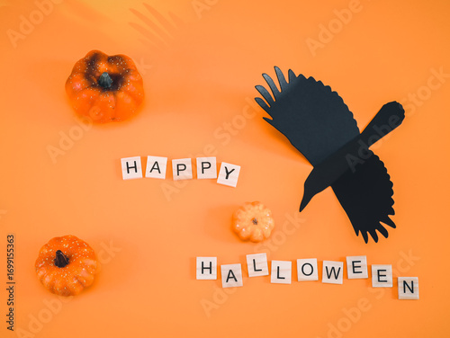 Wooden happy halloween cubes, crow and pumpkin on orange.