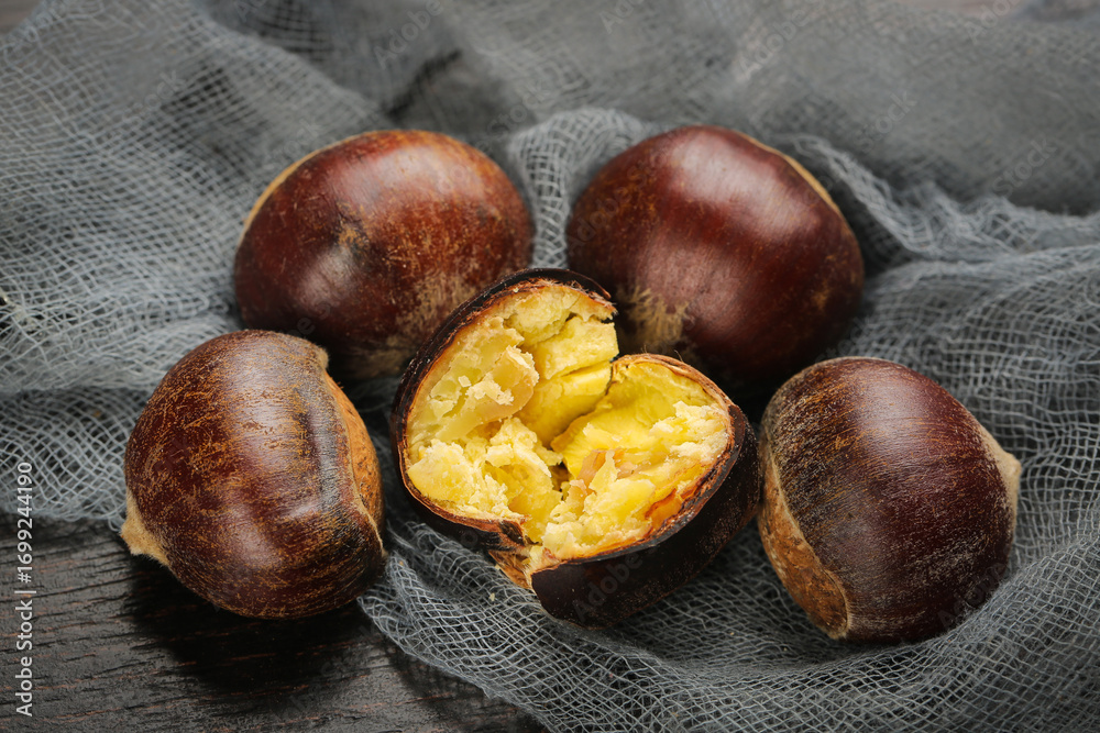Obraz premium Fresh Roasted Chestnuts with Cracked Shell Showing Golden Interior on Rustic Burlap