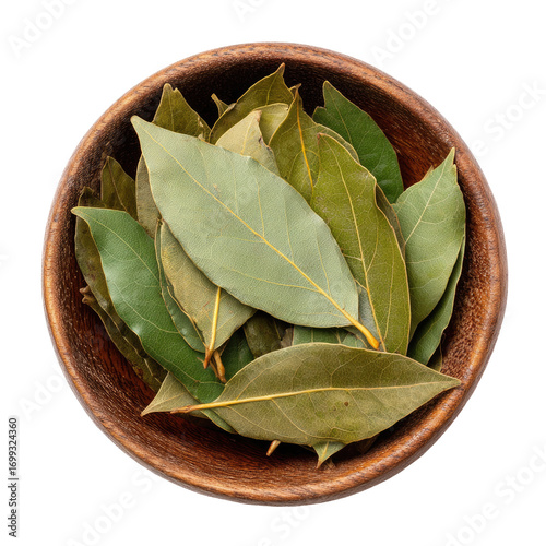 Dried bay leaves in a wooden bowl.  Fresh green and light brown leaves clustered in a shallow, round, wooden bowl.  Flat lay, top-down view, against a pure black background
