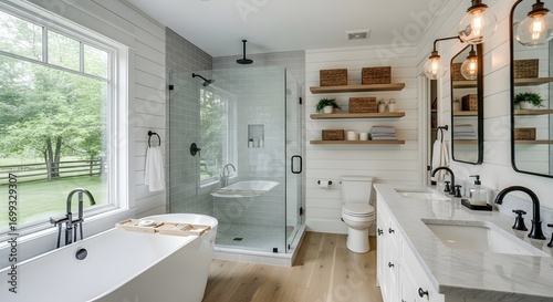 A bright and airy bathroom features white cabinets, quartz countertops, a freestanding tub, a frameless walk in shower, and wood look flooring. Natural light streams in