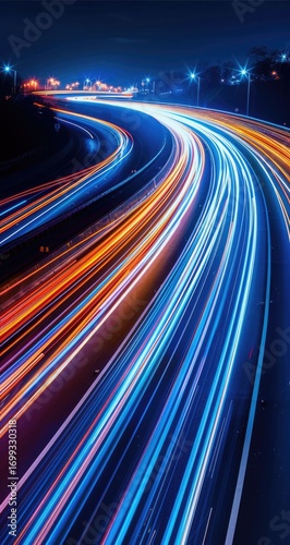 Night cityscape with vibrant light trails of vehicles curving along a highway, creating dynamic streaks of color against a dark background