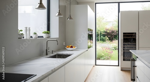 Bright minimalist kitchen featuring white cabinetry, marble countertops, and a large window overlooking a lush green garden. Natural light bathes the space. 
