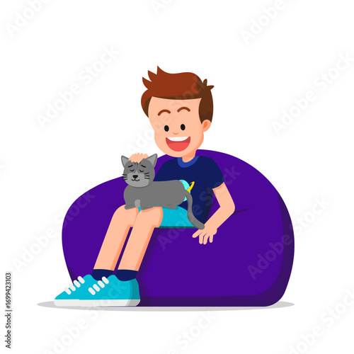 A boy sits on a beanbag with a sleeping cat on his lap