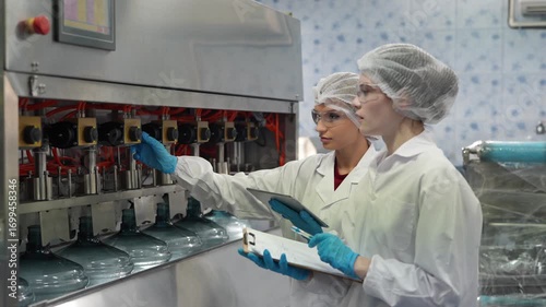 woman factory worker sterile uniform manufacture drink water. Female specialist factory line for processing and checking bottles water. Industrial product manufacturing aqua drink.