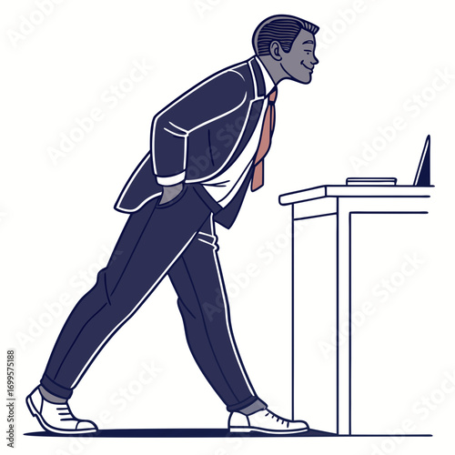 Smiling businessman leaning over a desk looking at a laptop with hands in pockets
