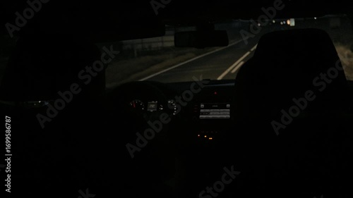 View of a nighttime car journey with dimly lit dashboard and empty road ahead, creating an atmosphere of intimacy, travel, and solitude.