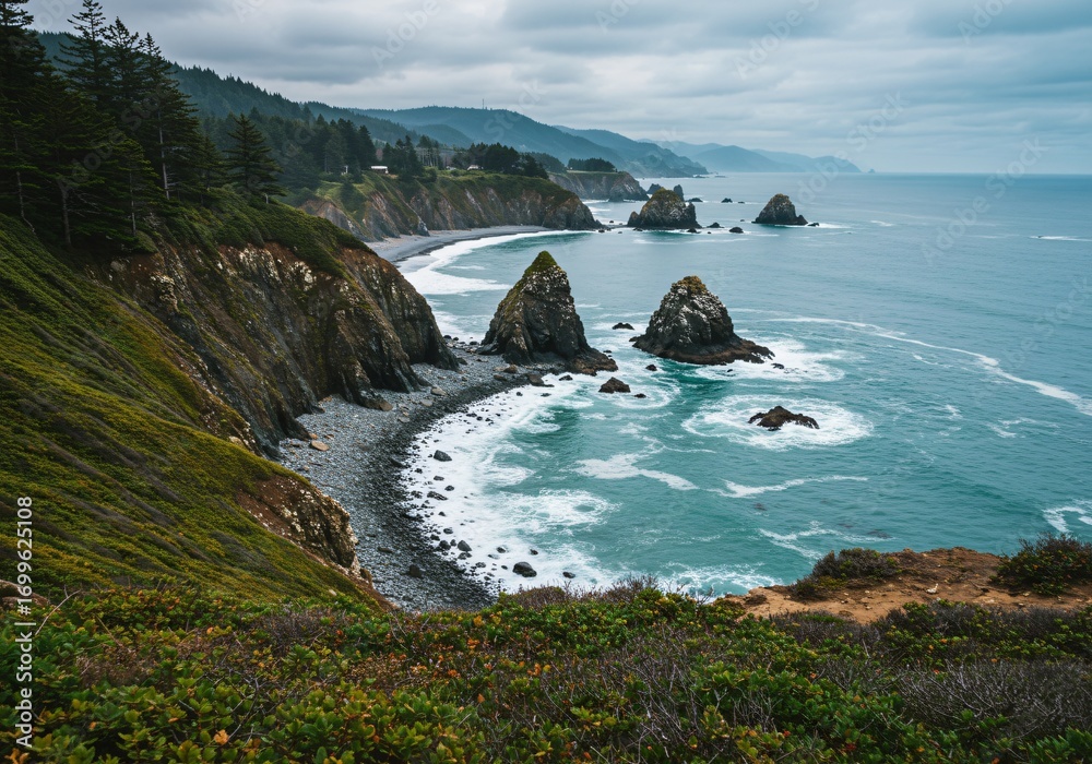 Obraz premium A dramatic view of a rugged coastline with towering sea stacks and green cliffs under a cloudy sky.