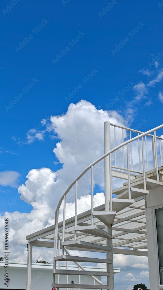 Naklejka premium Outdoor spiral staircase with blue sky.