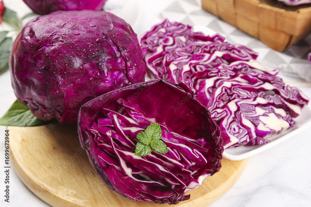 Obraz premium Fresh Purple Red Cabbage Heads Whole and Sliced on Wooden Cutting Board