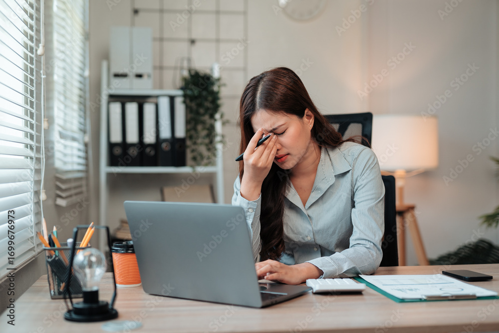 Young Asian office worker feeling tired, rubbing her eyes, suffering ...
