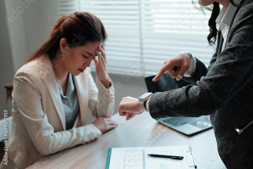 Foto Stressed employee suffering headache while manager pointing at smartwatch and bl