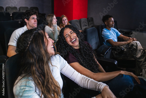 Group of friends having fun watching a comedy movie at the cinema, laughing out loud and enjoying the show