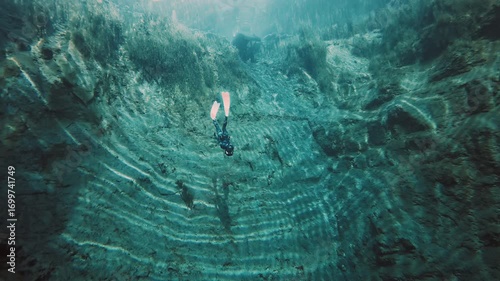 Freediver in the karst lake. Woman freediver swims underwater in the crystal clear lake named Goluboye Ozero near the city of Samara, Russia