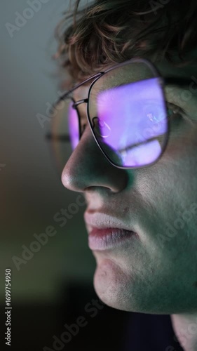 Vertical screen extreme closeup of man wearing reflective glasses staring at digital display with bright colors as artificial intelligence provides insights for technology research and data analysis