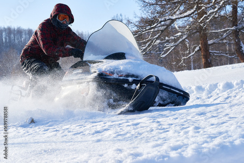 фотографія Young adult man riding snowmobile through snowy landscape, wearing protective go